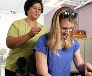 A CNT researcher applies an electrified patch to the back of the neck of a seated CNT study participant