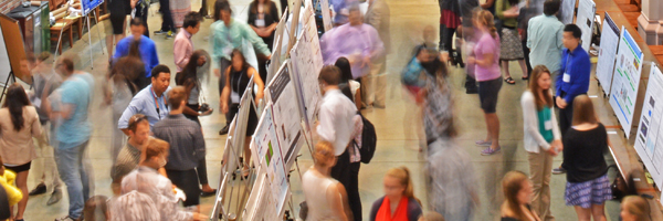 Abstract photograph of people speaking to each other at a conference poster session.