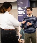Two people discussing in front of a sign that says "Healthy Aging"