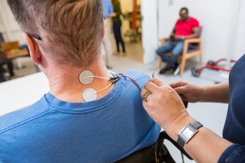 Back of the neck of a person with transcutaneous electrodes attached.