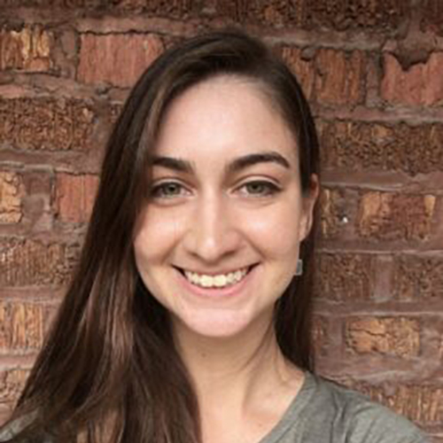 Headshot of Nora Shipp in front of a brick wall.