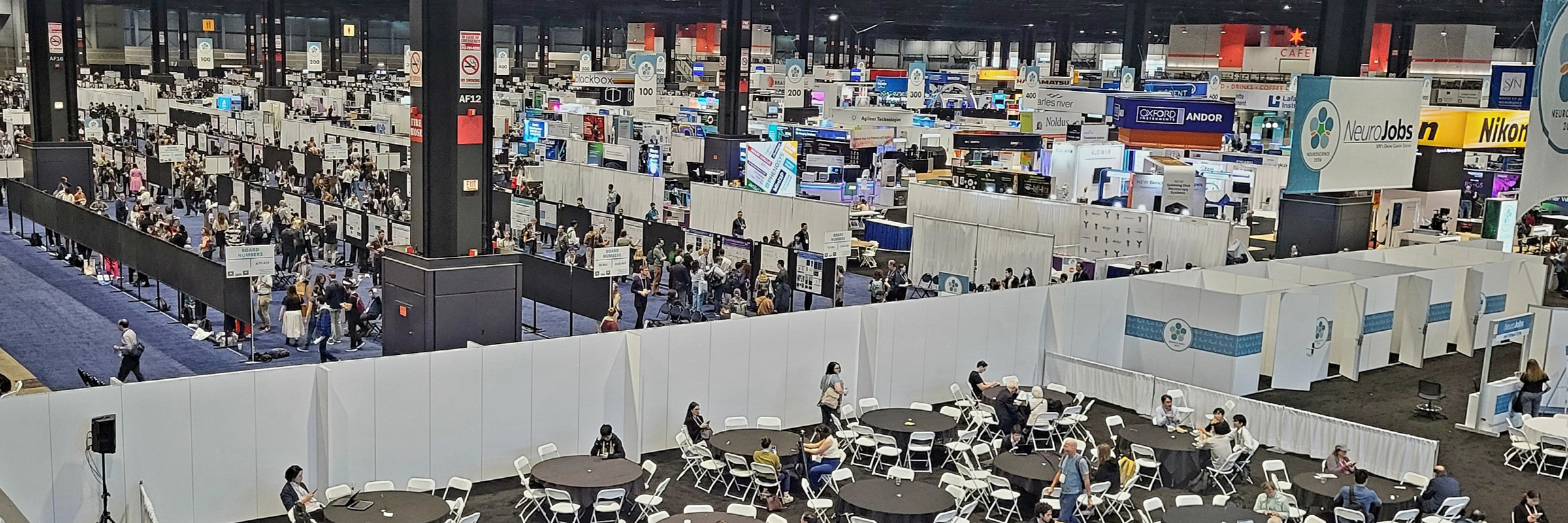 Busy conference exhibit floor with dozens of people around booths.