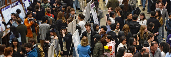 A crowd of people looking at posters at a conference.