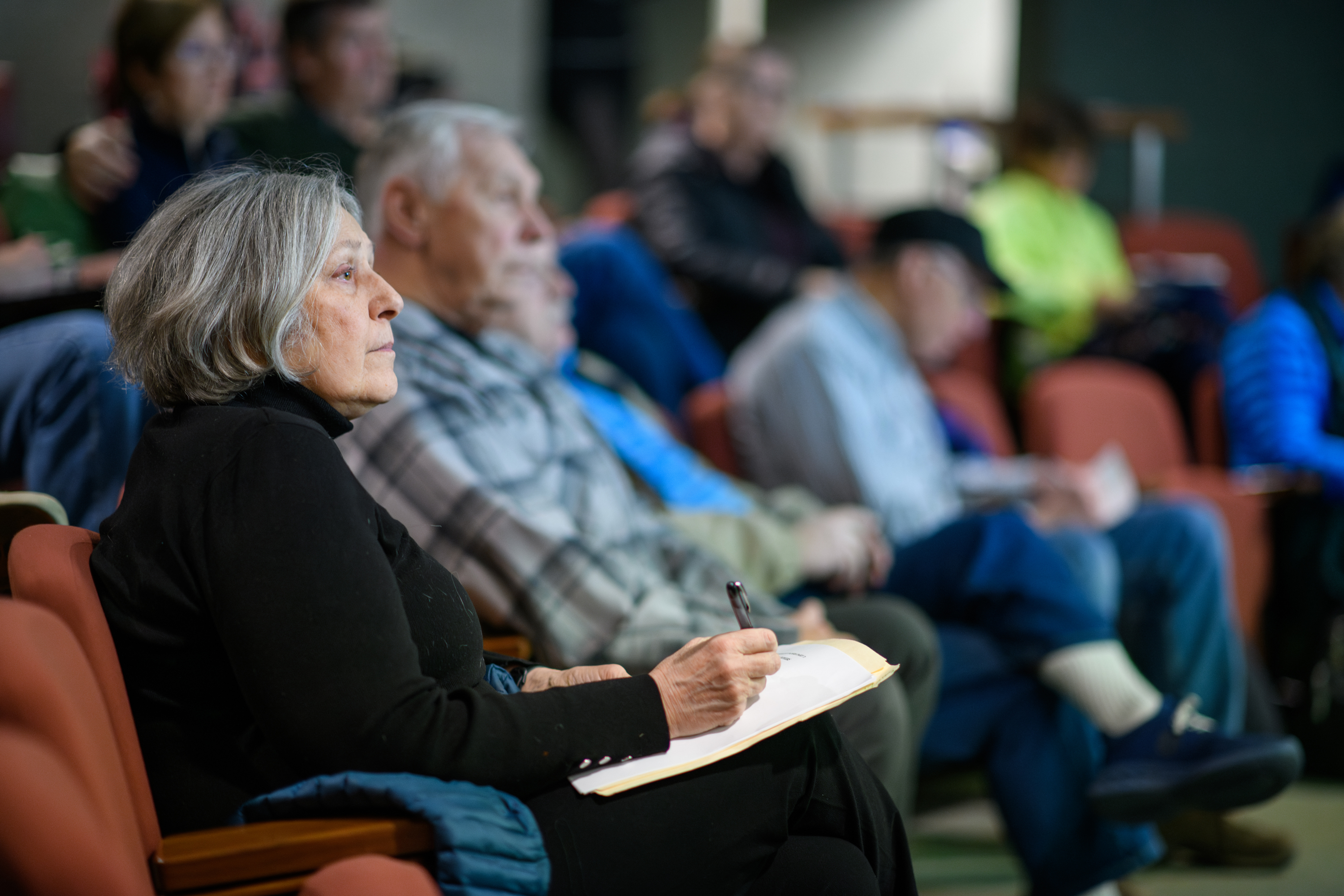 Two people sitting in chairs listening to a lecture.