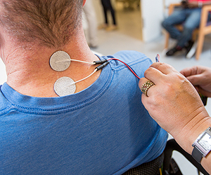 Electrodes on the back of the neck of a person sitting in a chair.