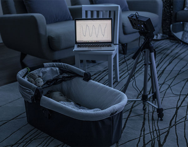 Sleeping baby with a smart speaker prototype monitoring its breathing